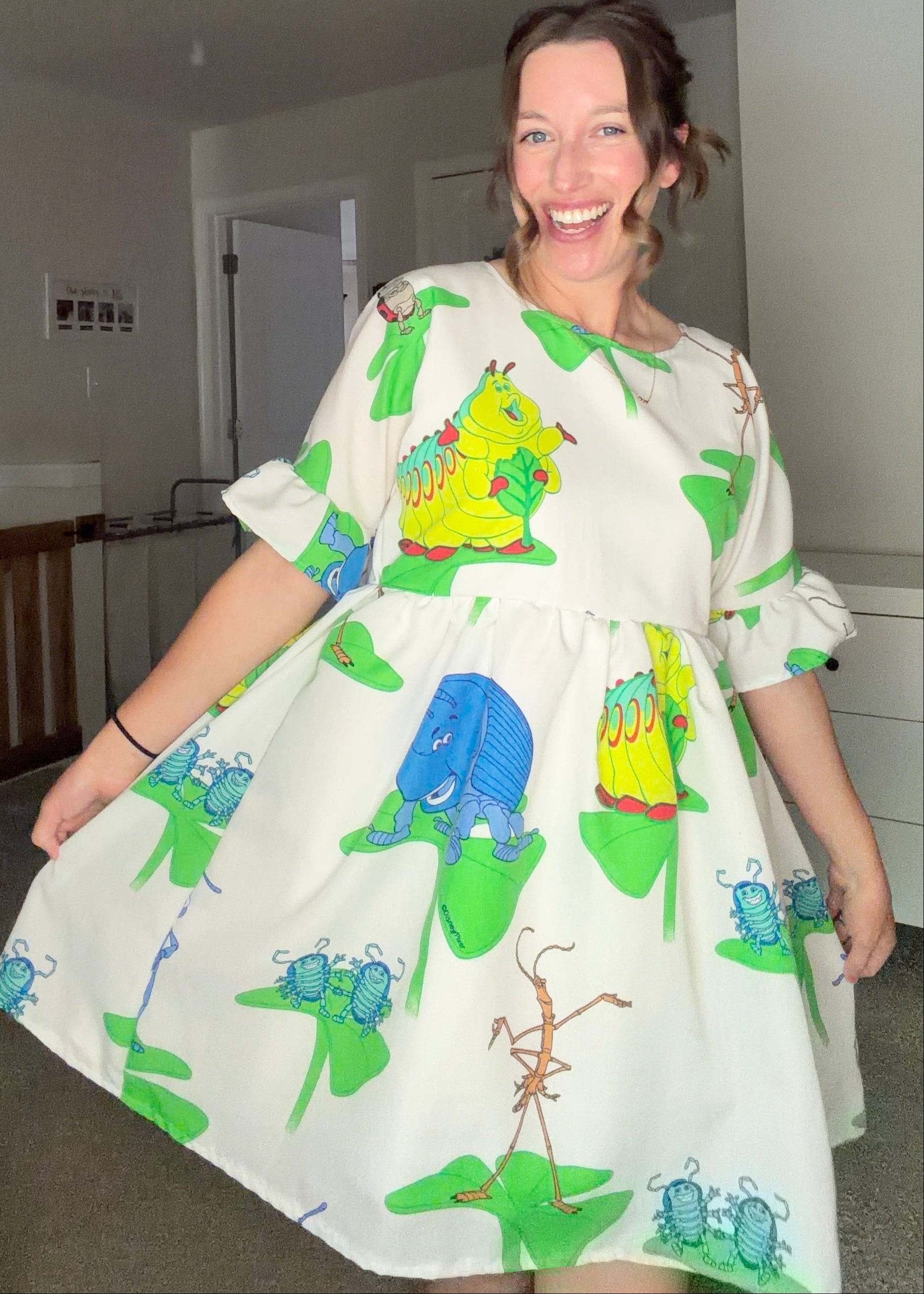 Woman wearing a dress with colorful caterpillar design in a room.