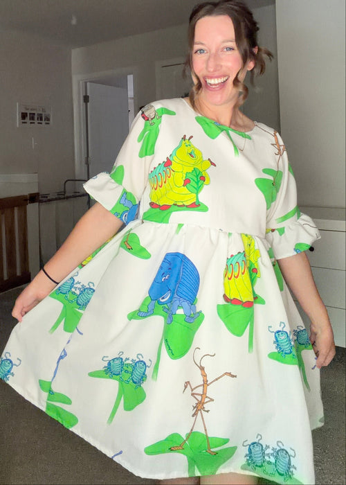 Woman wearing a dress with colorful caterpillar design in a room.